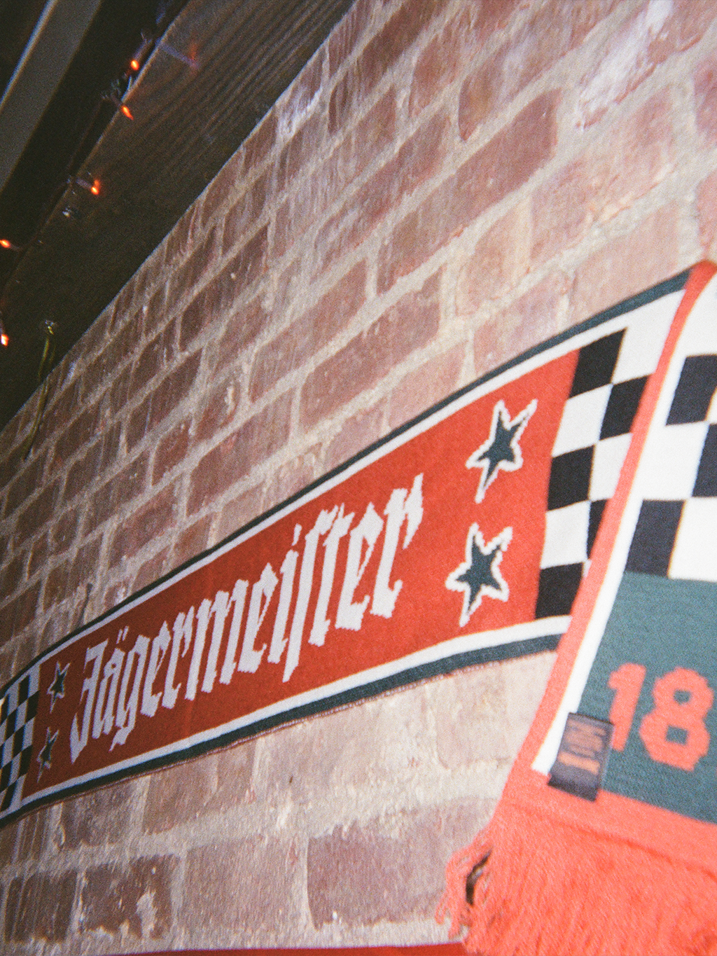 Jägermeister Racing-sjaal tegen een bakstenen muur.