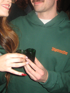 Persoon in een groene Jägermeister hoodie met de oranje Jägermeister-woordmarkering op de borst.