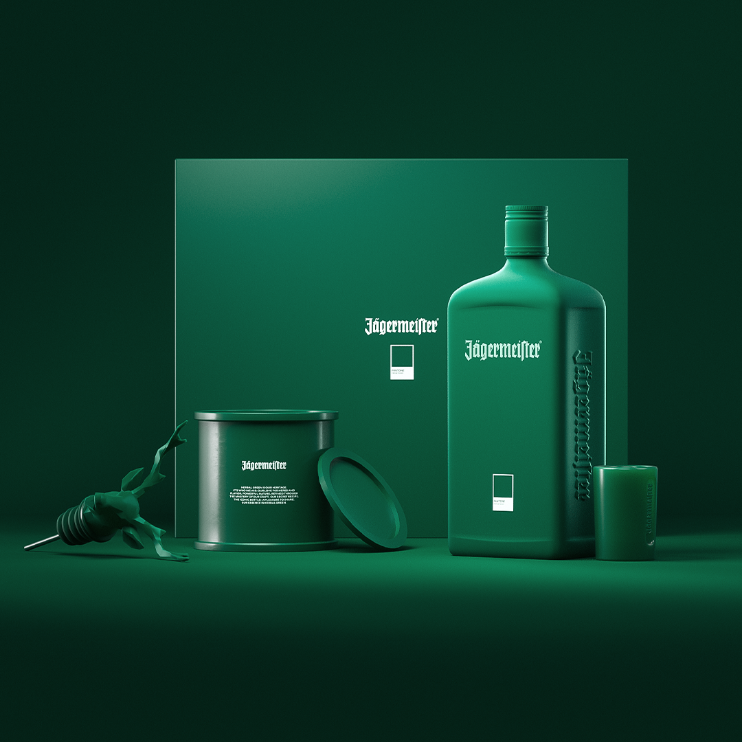 A coordinated Jägermeister product display in monochrome deep green, featuring a large bottle, a cylindrical tin with its lid leaning beside it, a small candle, and a decorative beetle, all arranged in front of branded packaging on a dark green studio background.