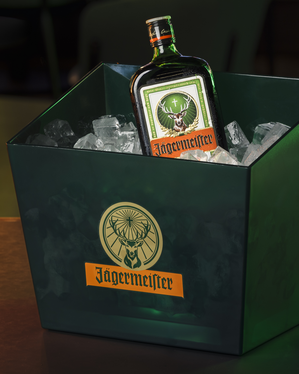Jägermeister-fles in een groene ijsbucket met zichtbaar logo.