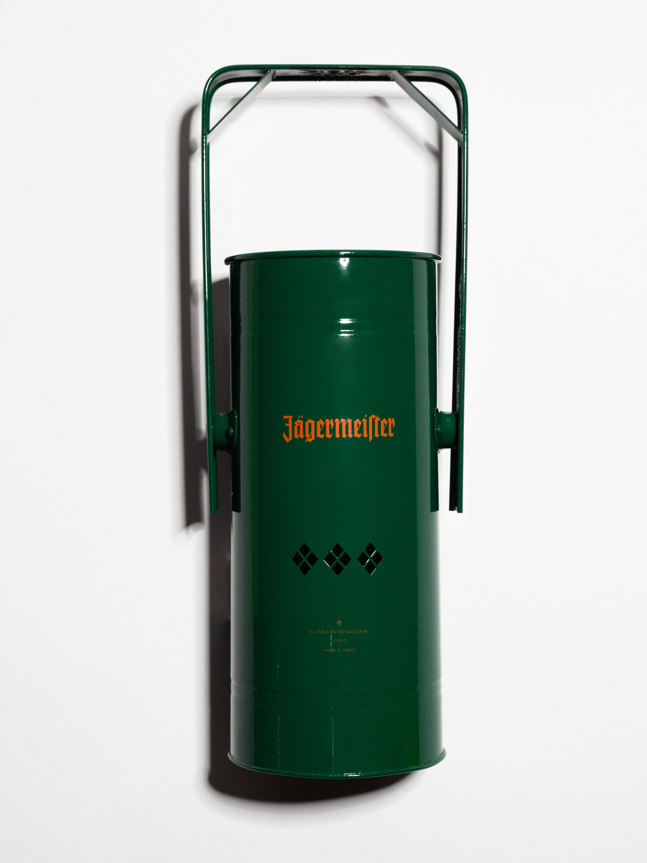 Groene metalen wierookbrander met handvat en oranje Jägermeister-logo op een witte achtergrond