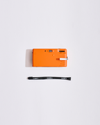 Oranje camera met een draagriem op een witte achtergrond