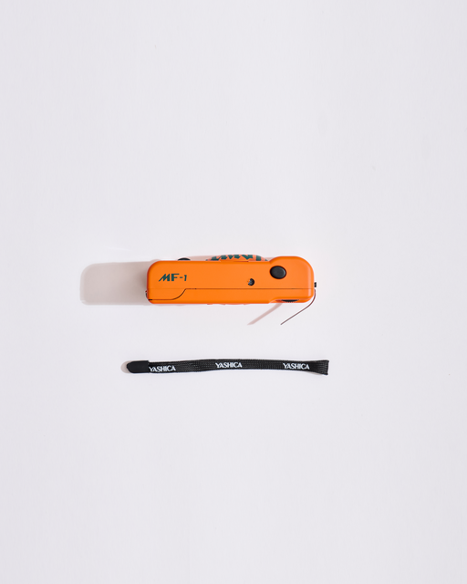 Oranje MF-1-apparaat met een zwarte draagkoord op een witte achtergrond