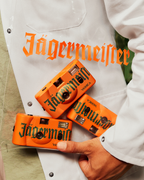 Drie oranje Jägermeister-camera's vastgehouden door een persoon in een witte jas.