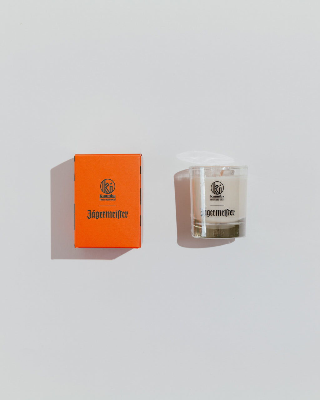 Jägermeister-kaars en oranje doos op een lichtgrijze achtergrond