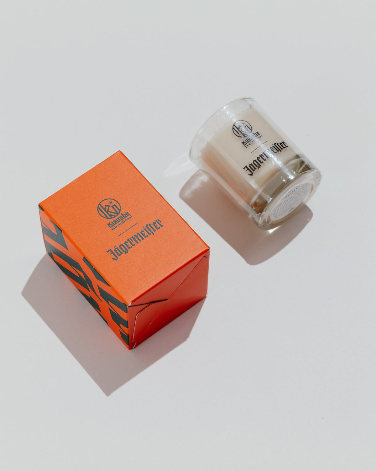 Jägermeister-kaars en oranje doos van bovenaf op een lichtgrijze achtergrond