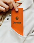 Jägermeister en Kuumba-logo op een oranje geurpapier, vastgehouden door een hand tegen een achtergrond van een witte jas