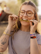 Vrouw met gouden Jägermeister-ketting en armbanden op een festival.