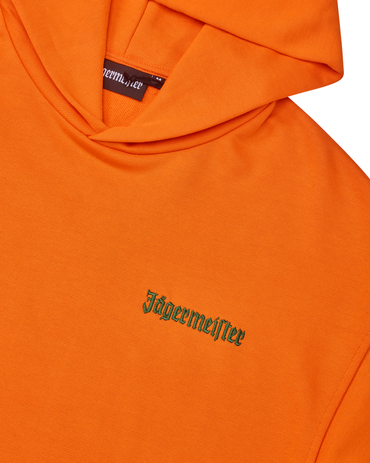 Oranje hoodie met groene Jägermeister-woordmarkering op de borst.