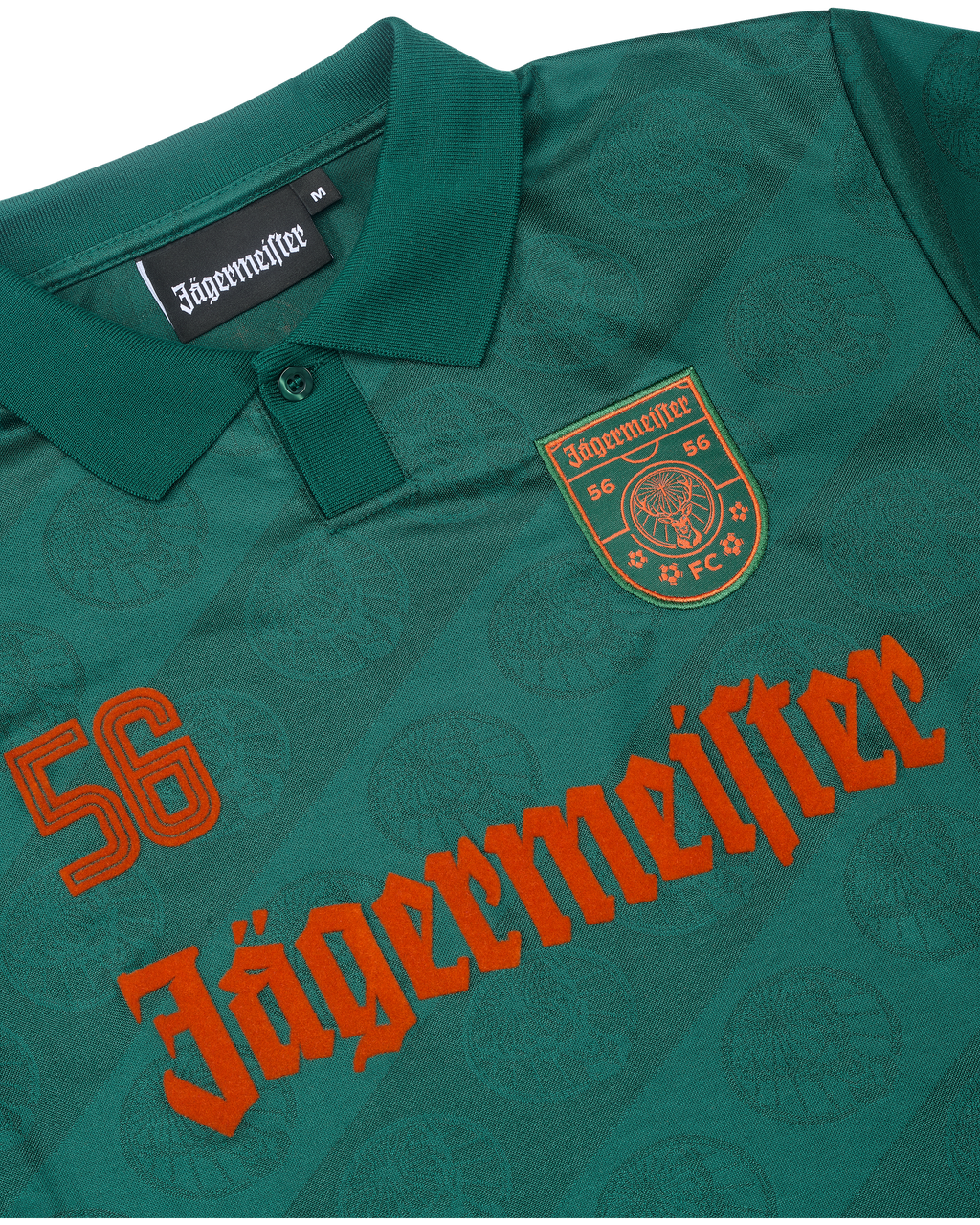 Close-up van een groen jersey met Jägermeister-branding.