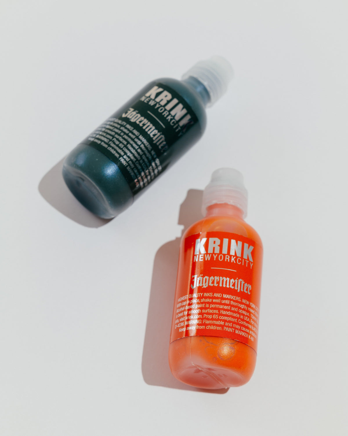 Two bottles of Krink markers, one green and one orange with Jägermeister branding.