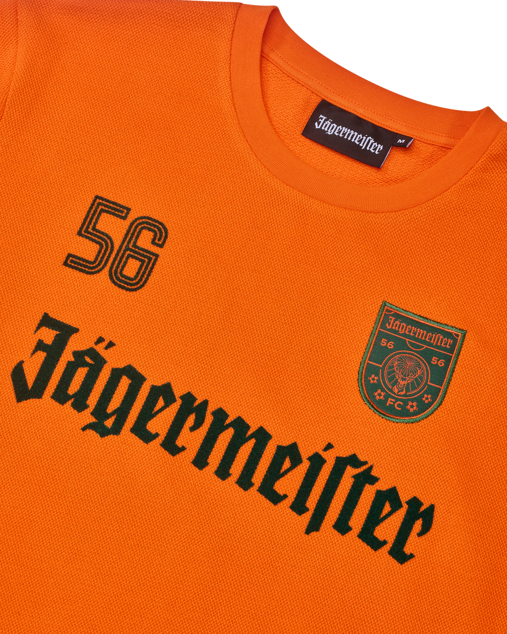 Oranje Jägermeister-longsleeve met zwarte Jägermeister-wordmark en een '56'.