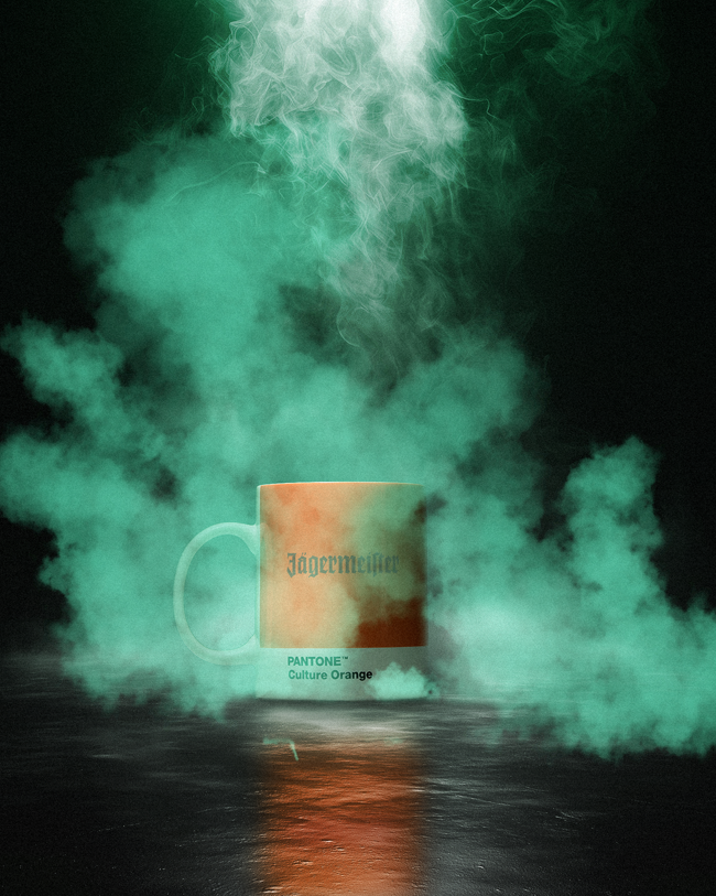 Mok met 'Jagermeister' en 'Pantone Culture Orange'-tekst, omringd door kleurrijke rook op een donkere achtergrond