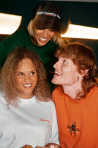 Drie mensen poseren samen, met focus op Jägermeister-kleding.