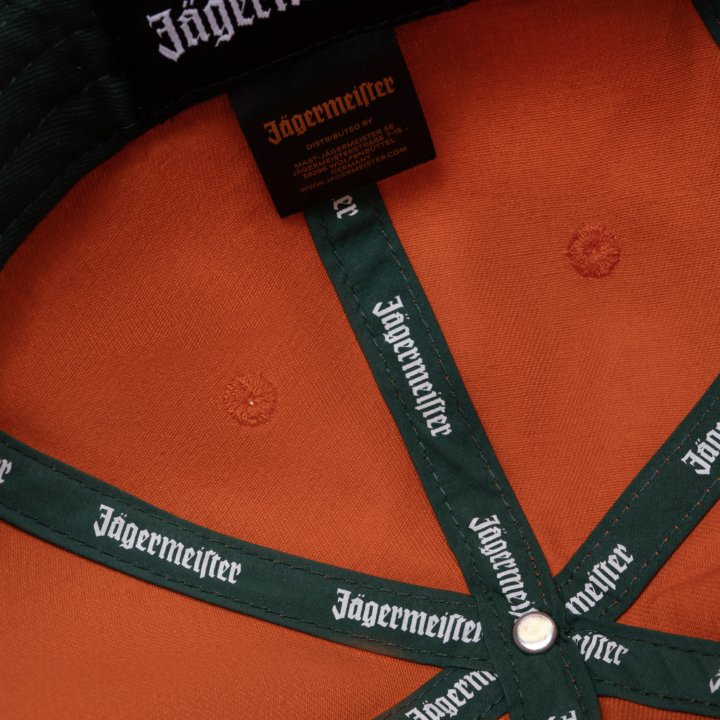 Oranje Jägermeister Racing-pet met Jägermeister-branding op de band en het label.
