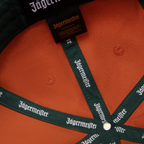 Oranje Jägermeister Racing-pet met Jägermeister-branding op de band en het label.