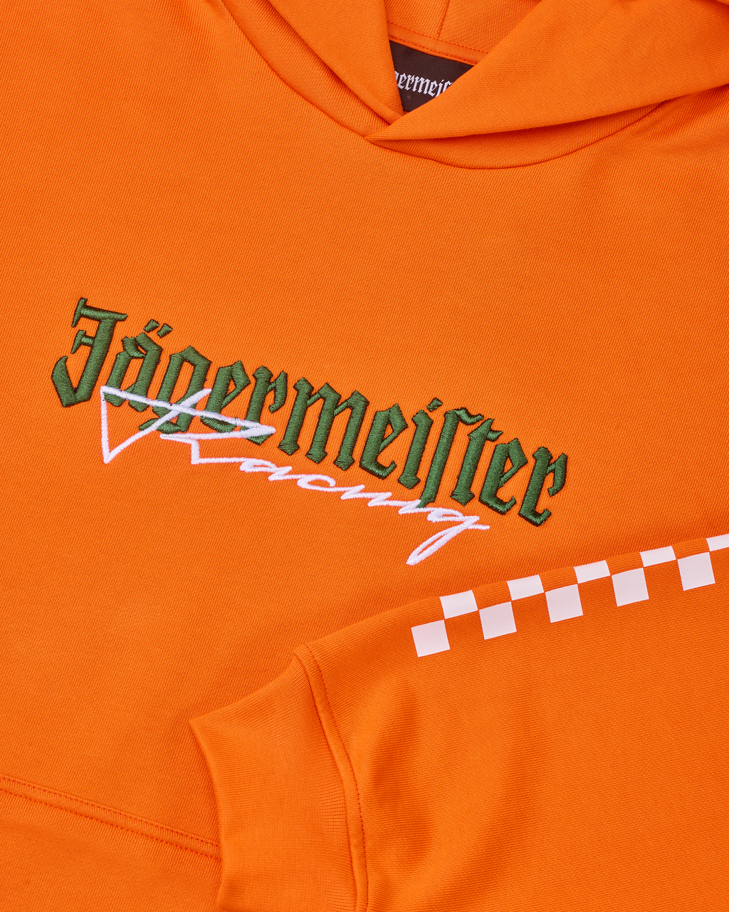 Oranje hoodie met een wit en groen Jägermeister Racing-logo.