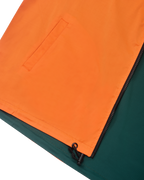 Close-up van een oranje en groene jas met een rits