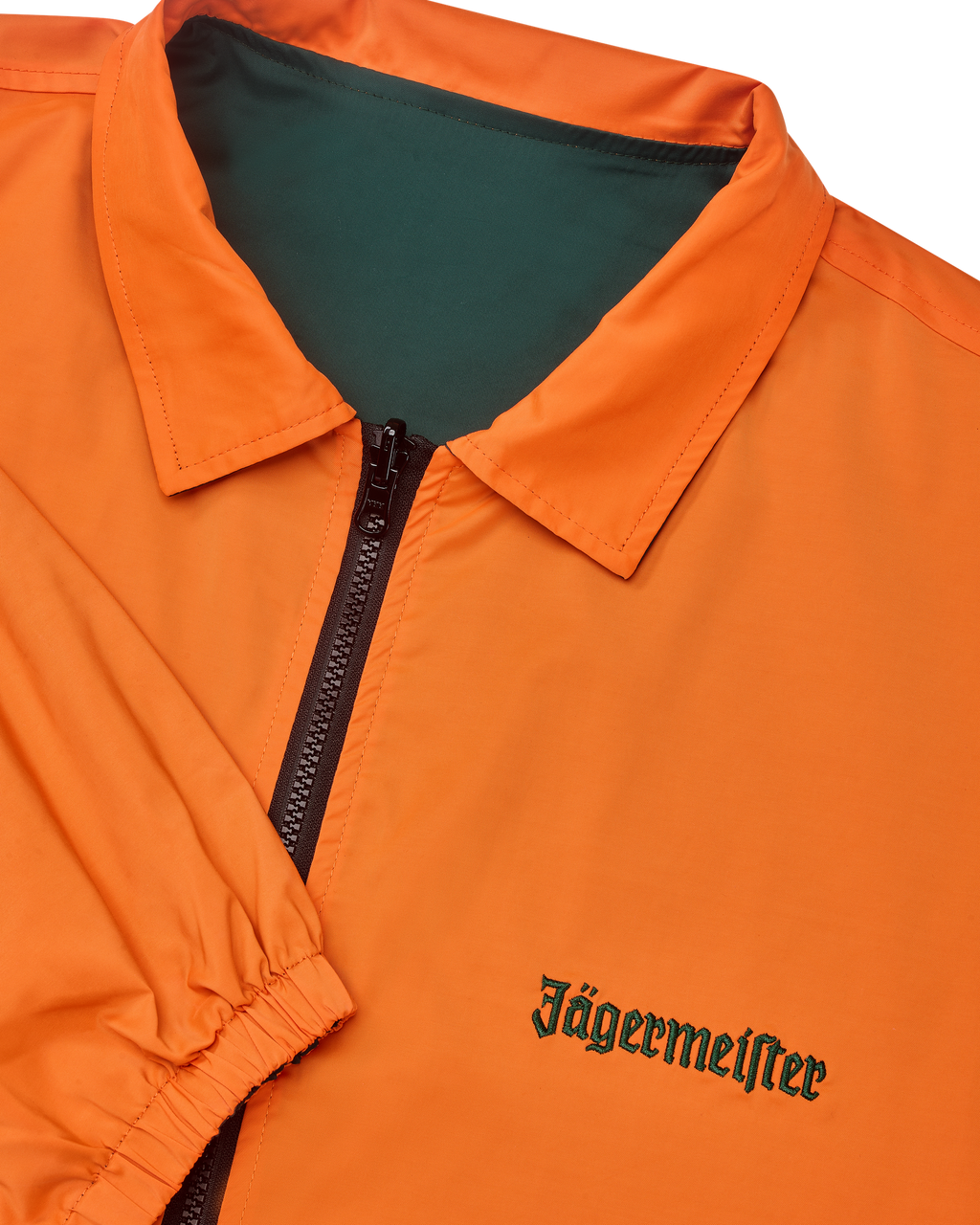Close-up van de omkeerbare Jägermeister-jas met een rits waarbij de oranje kant zichtbaar is