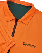 Close-up van de omkeerbare Jägermeister-jas met een rits waarbij de oranje kant zichtbaar is
