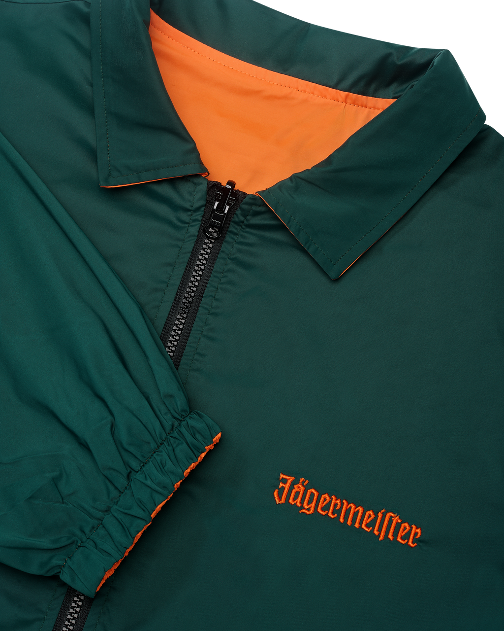 Close-up van de omkeerbare Jägermeister-jas met een rits waarbij de groene kant zichtbaar is
