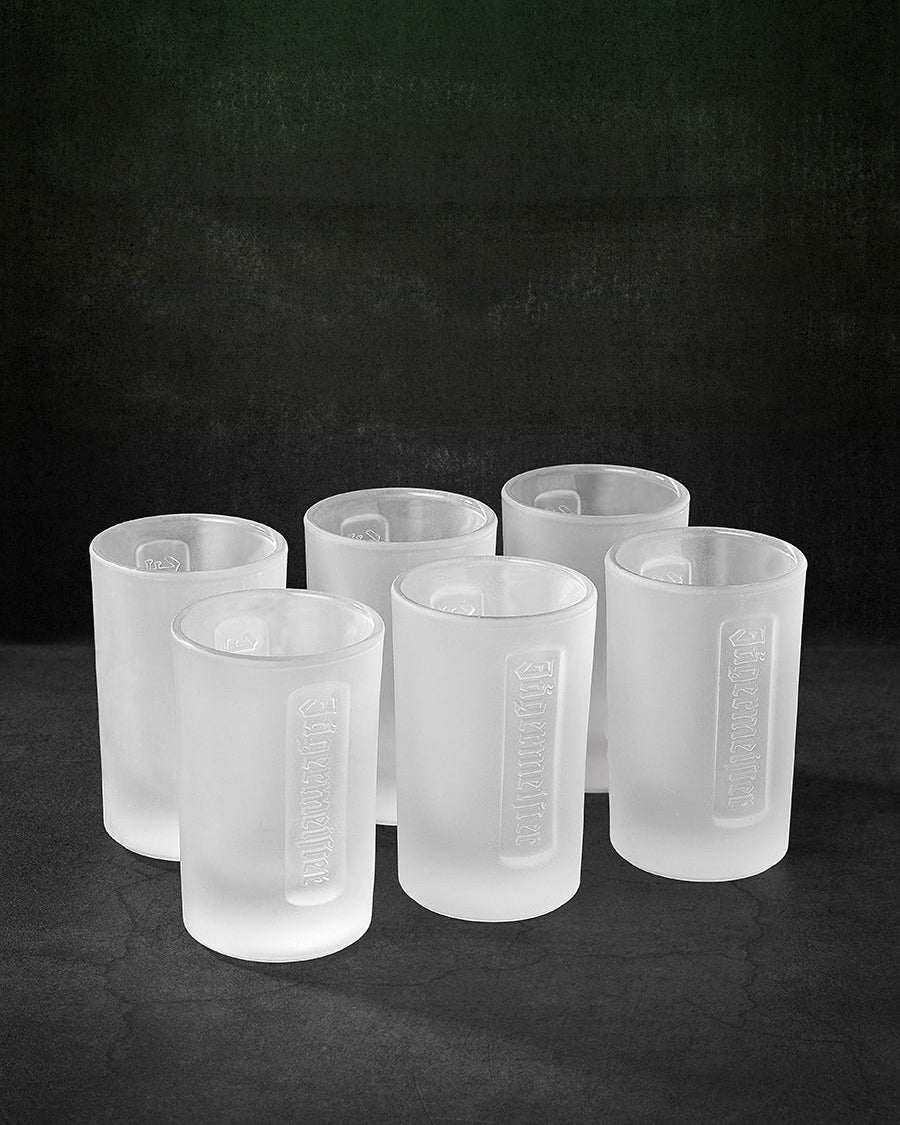 Set of six white Jägermeister shot glasses on a black background