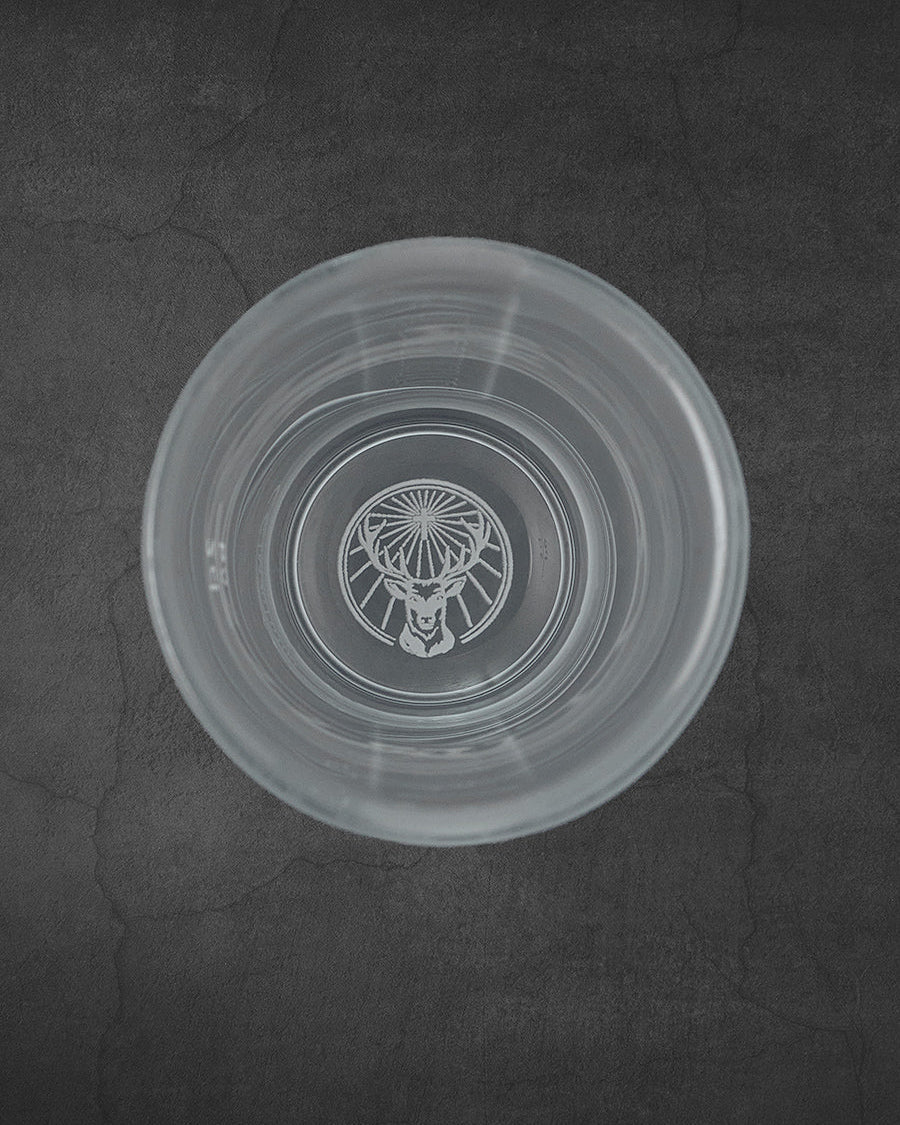White Jägermeister shot glas from the top with stag logo on the bottom
