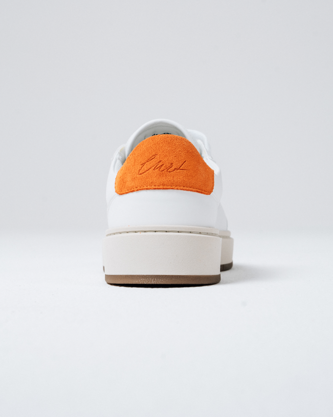A white Jägermeister sneaker shown from the rear, featuring a vibrant orange suede heel tab with the sneaker name 'Curt' embroidered in brown, a thick off-white midsole, and a brown outsole.