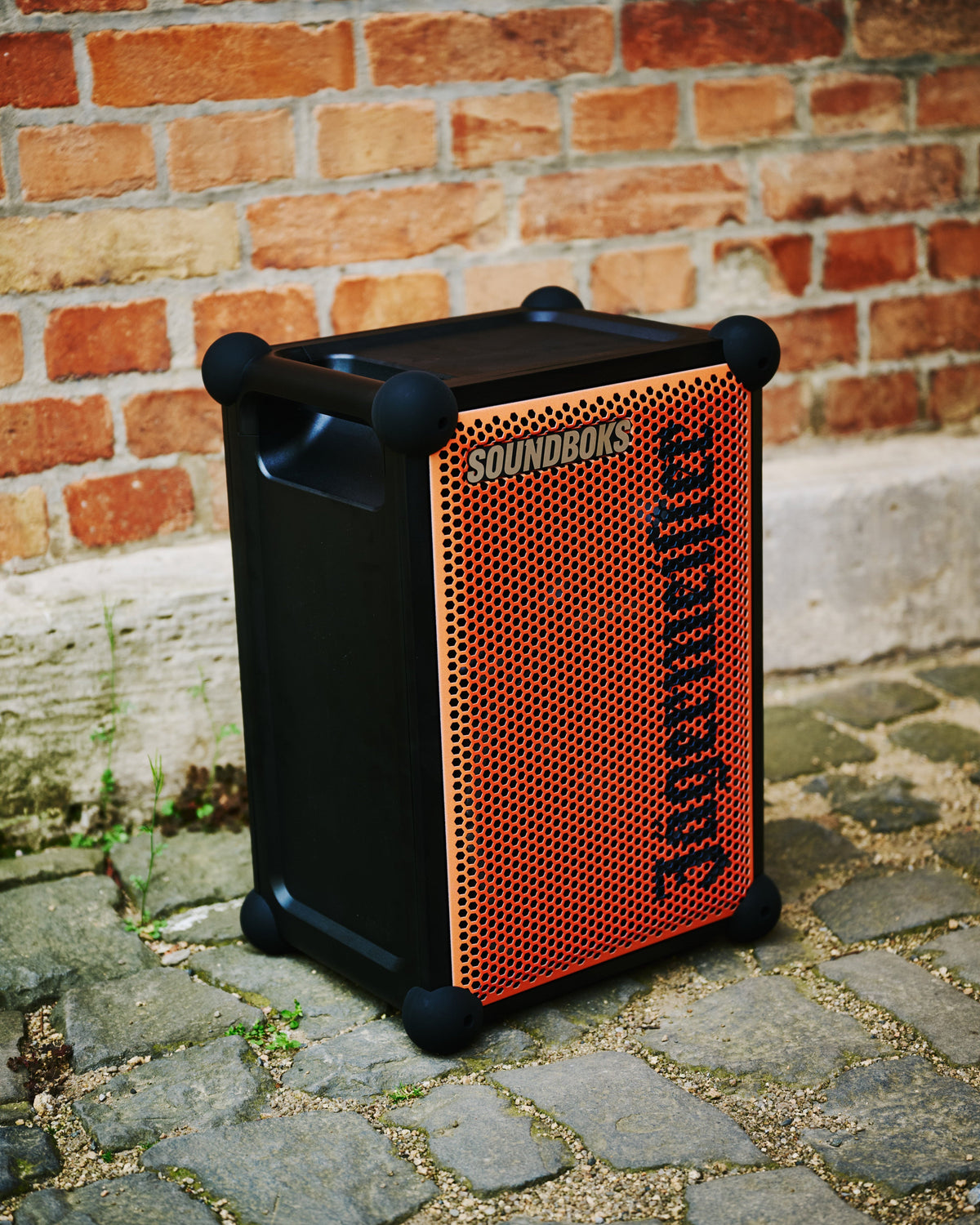 Orange and black portable Soundboks speaker with 'Jägermeister' branding against a brick wall