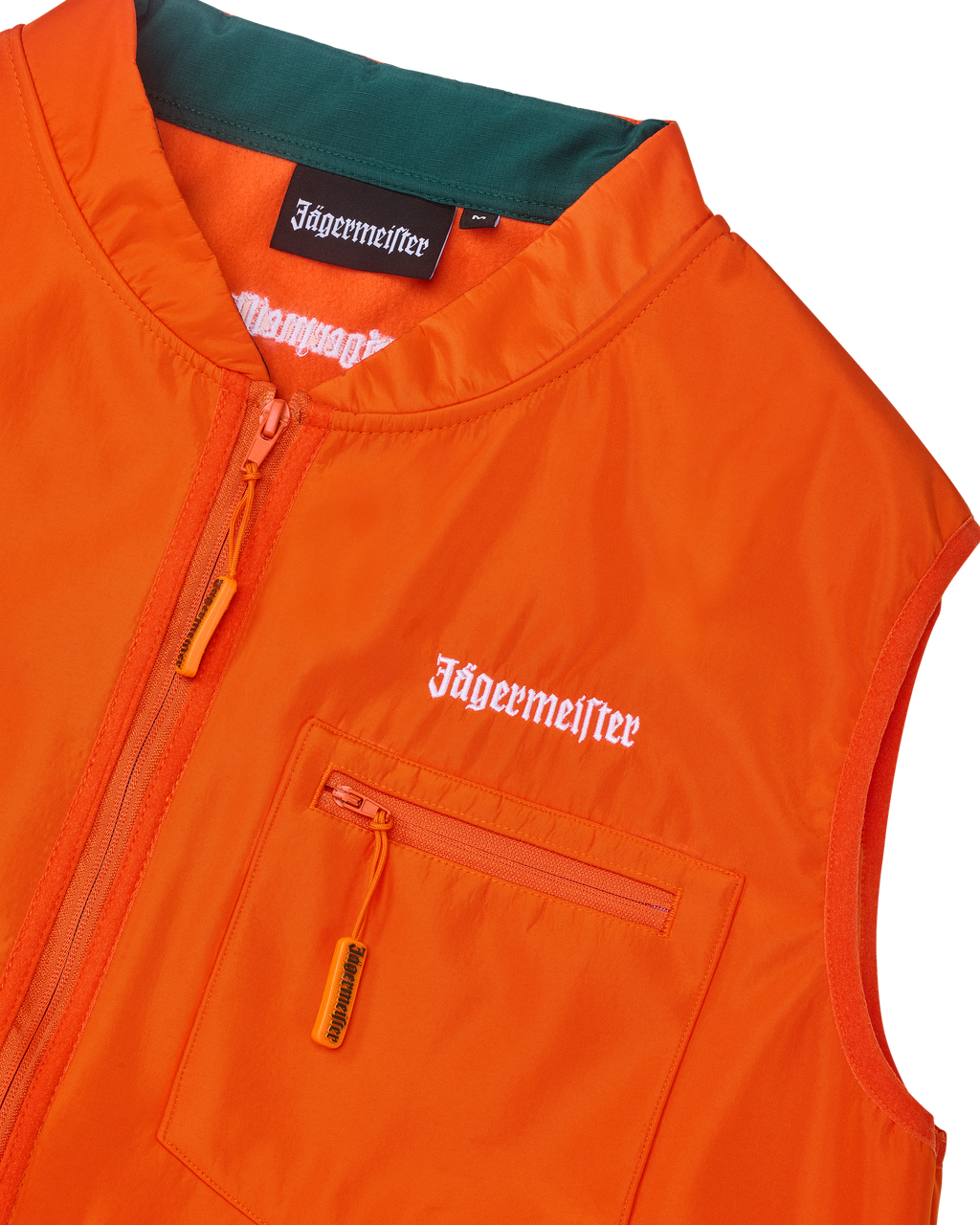 Close-up van een oranje vest met witte Jägermeister-branding.