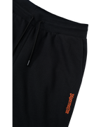 Zwarte trainingsbroek met oranje Jägermeister-logo op de zijkant.