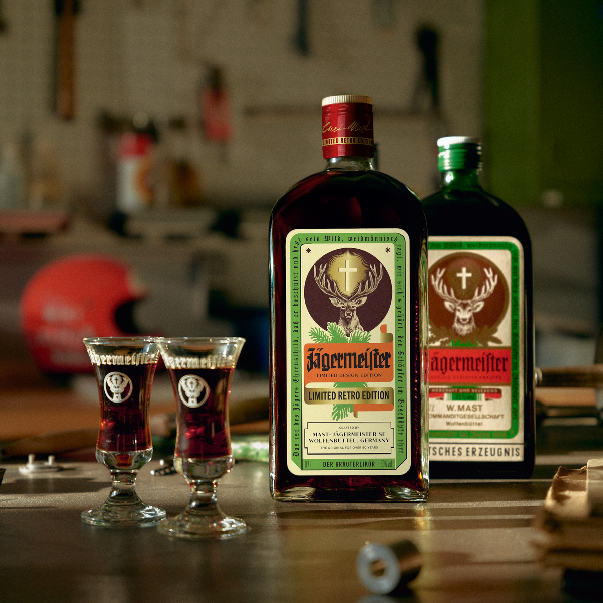 Two retro-bottles of Jägermeister with two matching glasses on a wooden surface in a dimly lit bar setting.